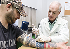 Dr. William Walker is seen with Joe Montanari, who served in the Army from 1999 â€“2008, including duty in Iraq.  Montanari works as a research assistant at the Richmond VA Medical Center. The TBI study led by Walker will include blood tests to check for certain genetic factors, in addition to brain scans, exams, and many other measures. (Photo by Jason Miller)   