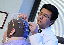 Dr. K. Luan Phan prepares a research participant for an EEG study. His lab is looking for brain patterns that predict how well a patient will respond to particular treatments for PTSD.  