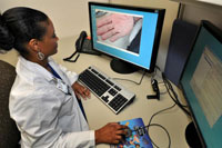 Porcia Love, MD, a dermatology resident at the Durham VA Medical Center and Duke University, examines an image and clinical notes documenting the skin rash of a patient at a remote location. (Photo by Linnie Skidmore)  