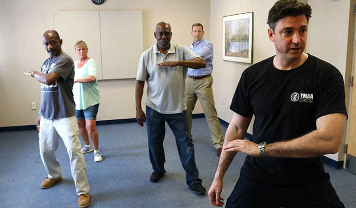 Tai chi instructor Brian Muccio demonstrates a movement with the help of a few VA employees who are also Veterans. The participants shown are not part of the ongoing Gulf War illness study. (Photo by Mackenzie Adams) ) 
