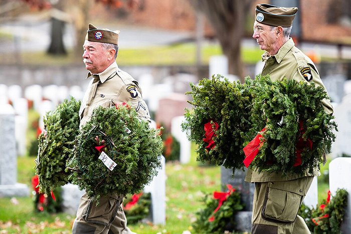 Veterans from the 101st Airborne Division (Air Assault) help place wreaths on graves of fallen service members during a 