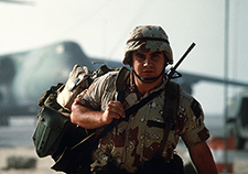A soldier carries his gear after arriving in Saudi Arabia during Operation Desert Shield.  