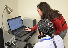 Click to enlarge Dr. Laura Manning Franke reviews EEG results with a research participant, who is wearing an electrode cap.