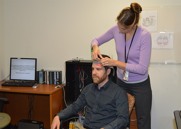 Dr. Mascha van't Wout-Frank, a neuroscience researcher at the Providence VA Medical Center in Rhode Island, demonstrates transcranial direct current stimulation with her colleague Dr. Noah Philip. <em>(Photo by Kimberly DiDonato-Ferro).