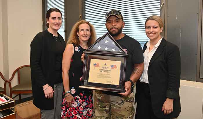 Veteran Wilfredo Santos displays a flag that flew above the U.S. Capitol in honor of Dr. Marianne Goodman, to his right. Accompanying them are study personnel Sarah Sullivan (left) and Angela Page Spears. (Photo courtesy of the James J. Peters VAMC) 