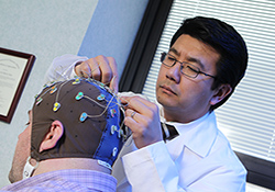 Dr. K. Luan Phan adjusts a volunteer's electrode cap. The researcher is studying the brain's 