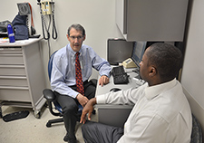      Dr. Howard Gordon, seen here with Air Force Veteran and VA employee Kevin Harris, says it can be a challenge when exam-room ergonomics force physicians to
    turn away from patients to use the computer. (Photo by Robert Gonzalez)