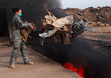  An airman tosses uniforms into a burn pit at Balad Air Base, Iraq, in 2008. The military burns unusable uniforms to make sure they don't end up in enemy hands.  