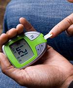 Woman testing her blood sugar level using a glucose meter.  