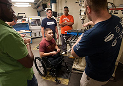   Veterans (from left) Keniel Martinez, Shawn O'Donnell, Artem Lazeckin, Gary Rethage, and Adam Benjamin Campbell listen to shop supervisor Garrett Grindle explain how to operate a drill press. 