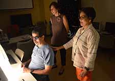 Joseph Coulter wears special goggles as he maneuvers two slides that make up a 3-D image until all of the image elements are aligned. Looking on are his wife, Jill (center), and occupational therapist Imelda Llanos.   