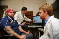 Brain Dr. Scott Sponheim (at computer) inspects EEG recordings of brain waves from OEF/OIF Veteran Andrew Lisdahl. Lab assistant Peter Lynn monitors electrode placement.