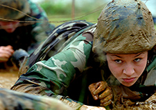 A Naval Academy midshipman crawls through the mud during 