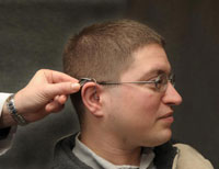 Army Veteran Louis Lamp wears an earpiece that is part of a frequency modulation system that helps him hear speech more clearly in noisy settings. (Photo by Michael Moody)  