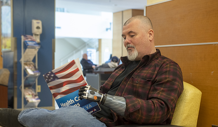 Army Veteran Robert Lewis, wearing a myoelectric arm, peruses a magazine at the VA Pittsburgh Healthcare System. (Photo by Bill George)  
