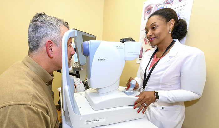 Nguyen Walker demonstrates the use of a digital retinal camera—an important part of remote eye screening—with Army Veteran  Bill Beverley-Blanco. (Photo by Lisa Pessin) 