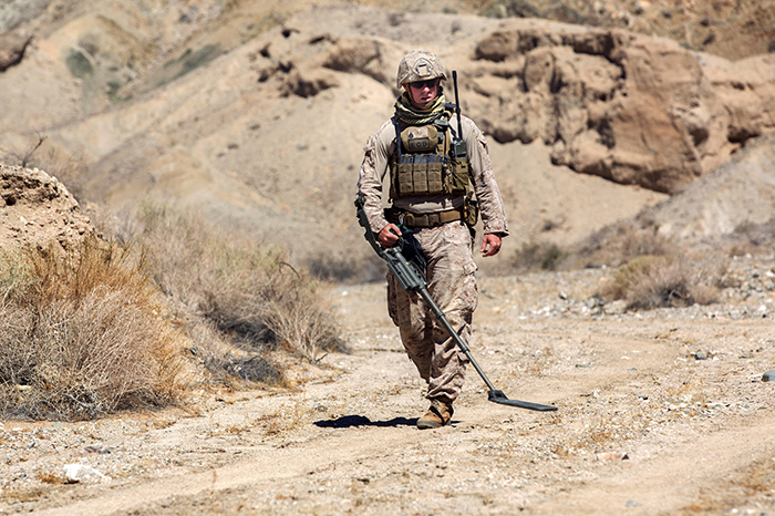 An explosive ordnance disposal technician performs a sweep with a metal detector during a post-blast analysis at a Marine training site in California. Blast exposure is common among service members, but its chronic psychiatric effects are not well-understood. (Photo by Marine Lance Cpl. Levi Schultz).