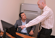 Dr. Matthew Smith (standing) chats with Army Veteran Adam Navarro-Lowery as he prepares to use a virtual reality job-interview training program. 