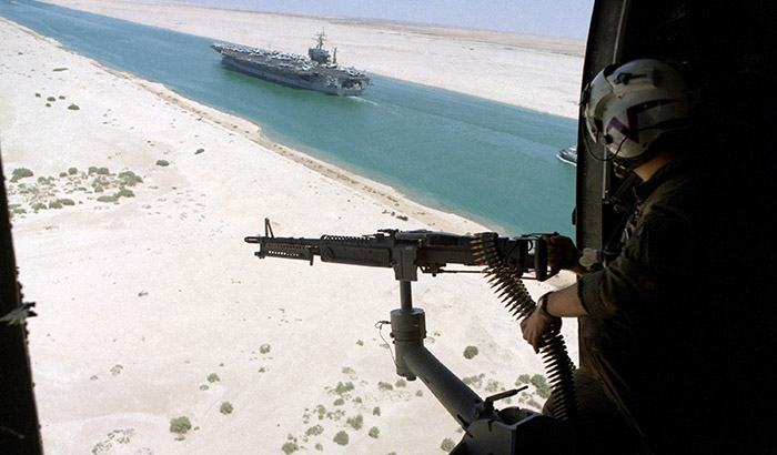 A helicopter gunner watches as the USS Eisenhower passes through the Suez Canal following a deployment in support of Operation Desert Shield in 1990.   