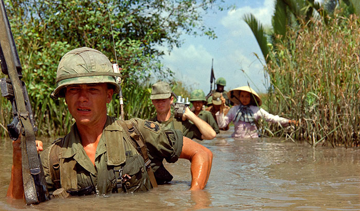 Private Fred L. Greenleaf crosses a deep irrigation canal during an allied operation during the Vietnam War. (Photo: National Archives) 