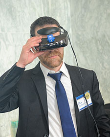 Dr. Noah Philip demonstrate part of a system that uses virtual reality to deliver therapy for combat Veterans with PTSD.  His research group at the Providence VA Medical Center is combining the technology with a form of brain stimulation. (Photo by Robert Williams)  