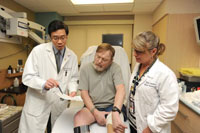 Veteran William Honse, center, confers with Dr. Andrew Liman and nurse practitioner Kelly Garbelotti about an experimental cell therapy that Honse is undergoing at the Pittsburgh VA Medical Center to try to save his leg from amputation. (Photo by Glenn Hangard)