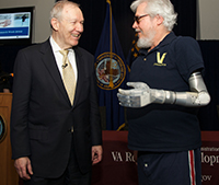 Dr. Joel Kupersmith shares a light moment with Vietnam-era Veteran Artie McAuley at a VA headquarters event during National VA Research Week in 2012. McAuley, who lost his arm in a car accident in 1969, participated in VA tests of the DEKA advanced prosthetic arm. (Photo by Emerson Sanders) 