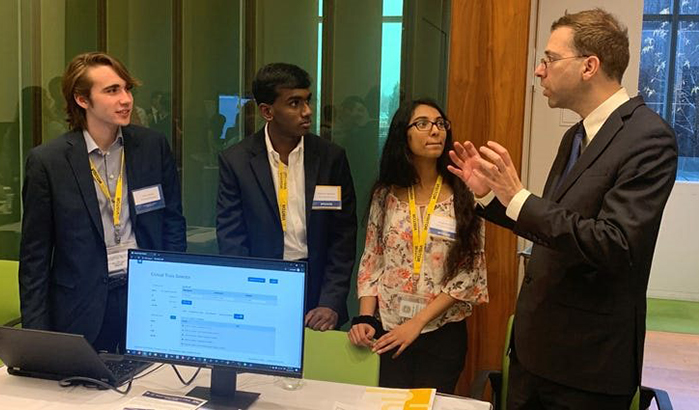 The Girls Computing League tech sprint team discusses the Clinical Trials Selector app with Dr. Gil Alterovitz. From left to right: Ethan Ocasio, Neeyanth Kopparapu, Shreeja Kikkisetti, and Alterovitz. (Photo was taken prior to COVID-19 pandemic.)