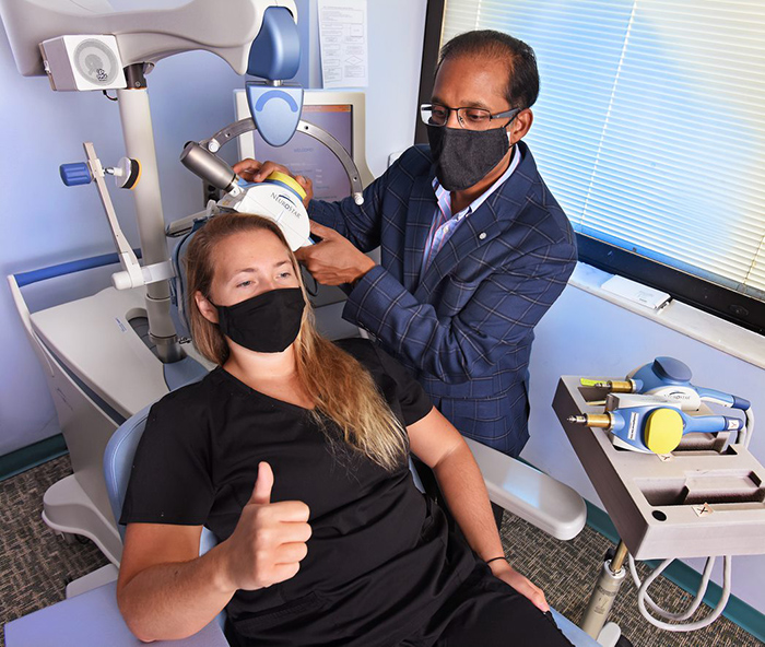 Dr. Prasad Padala simulates repetitive transcranial magnetic stimulation for mapping the brain of a research assistant at the Central Arkansas VA, Ashlyn Jendro. She's holding her thumb up to indicate the twitching caused by the pulses. (Photo by Jeff Bowen)