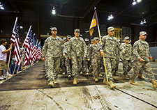 Family and friends hold American flags for soldiers as they march through the doors of a hangar at Stout Field in Indianapolis after returning home from deployment to Afghanistan. (Photo by Virin, U.S. Department of Defense)